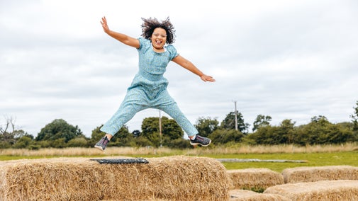 Child in blue jumpsuit playing on straw bales, Attingham Park, Shropshire